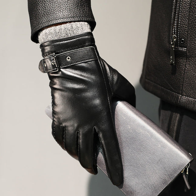 Person wearing black leather gloves holding a silver clutch against a neutral background