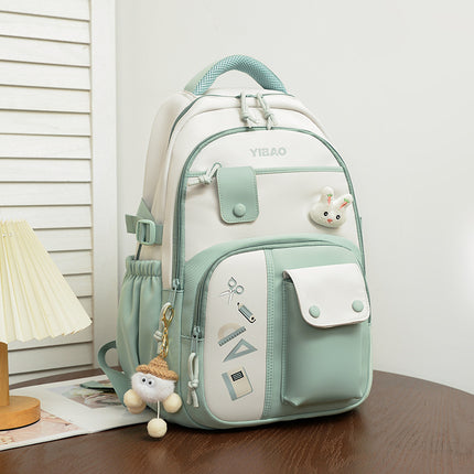 Light green and white backpack with decorative elements on a wooden surface.