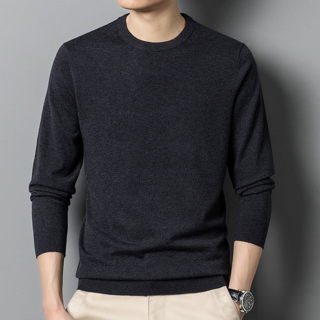 Person wearing a dark gray sweater against a gray background