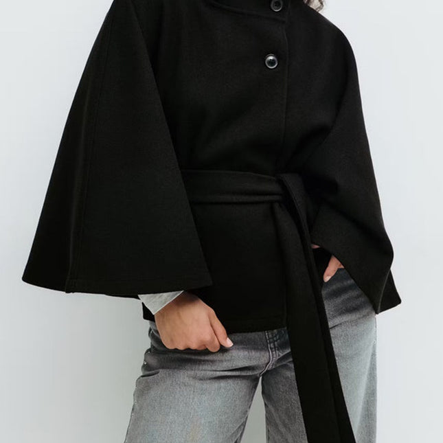 Person wearing a black cape over a plain background