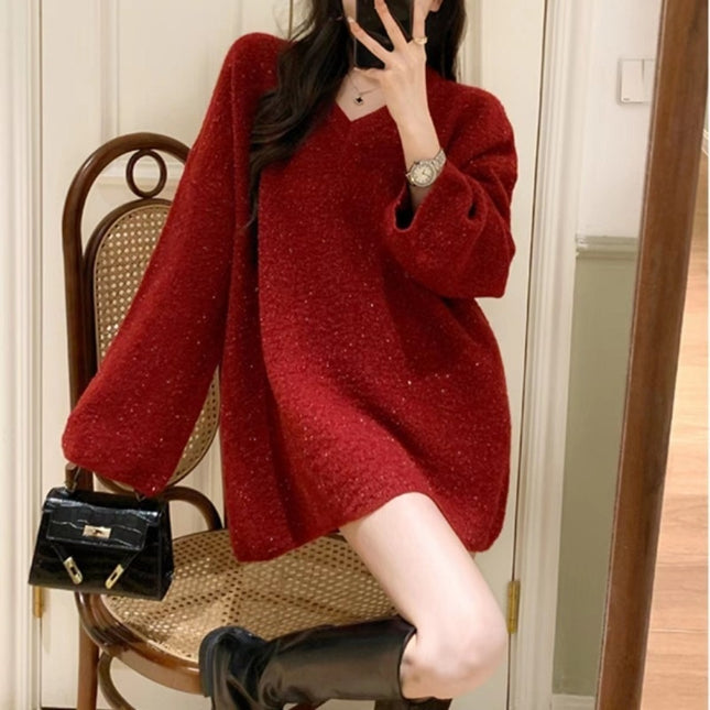 Person wearing a red sweater sitting on a chair with a black handbag beside them.