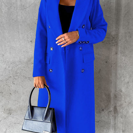 Person wearing a blue coat holding a black handbag against a gray concrete wall.