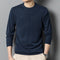 Person wearing a navy blue sweater against a gray background