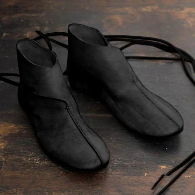 Pair of black leather shoes on a wooden surface