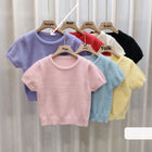 Colorful baby sweaters on hangers with labeled colors against a neutral background