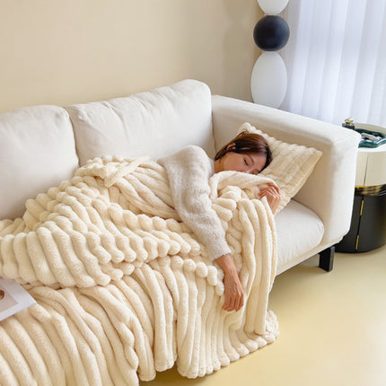 Person lying on a couch under a fluffy white blanket in a cozy living room.