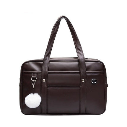 Dark brown handbag with a white pom-pom on a white background