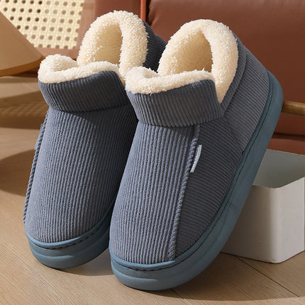 Pair of gray slippers with white fur lining on a wooden floor.