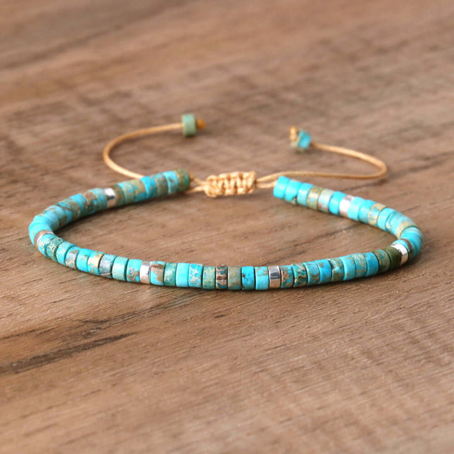 Turquoise spacer bead bracelet with adjustable gold-tone closure on wooden background.