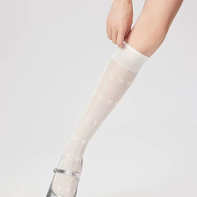 White fishnet knee-high socks worn by a person on a light gray background