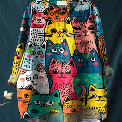 Colorful cat-patterned shirt on a hanger against a dark background