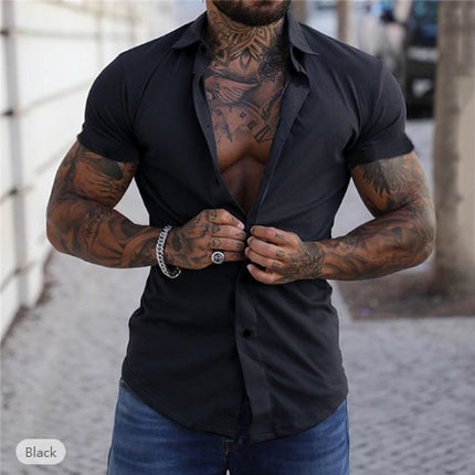 Man with tattoos wearing a black shirt and blue jeans outdoors