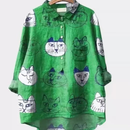 Green shirt with cat pattern on a hanger against a white background