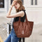 Woman holding a brown leather tote bag in an urban setting
