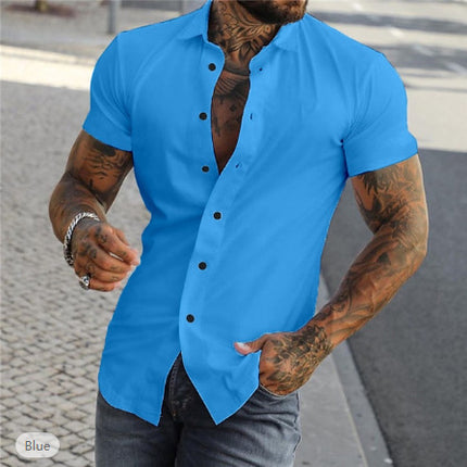 Man wearing a blue short-sleeve shirt with tattoos on arms, standing outdoors.