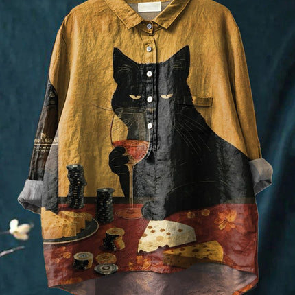 Yellow shirt with a black cat and wine glass design on a hanger against a dark background