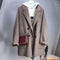 Brown coat with a red handbag on a mannequin against a gray background