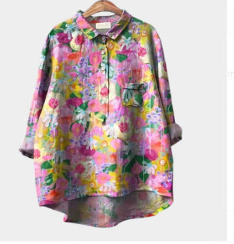 Colorful floral blouse on a hanger against a white background