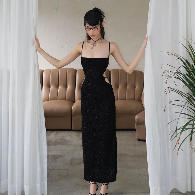 Woman in a black dress standing between two white curtains in a room with a beige sofa.