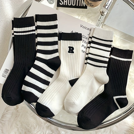 Set of black and white striped socks on a glass surface with a magazine underneath.