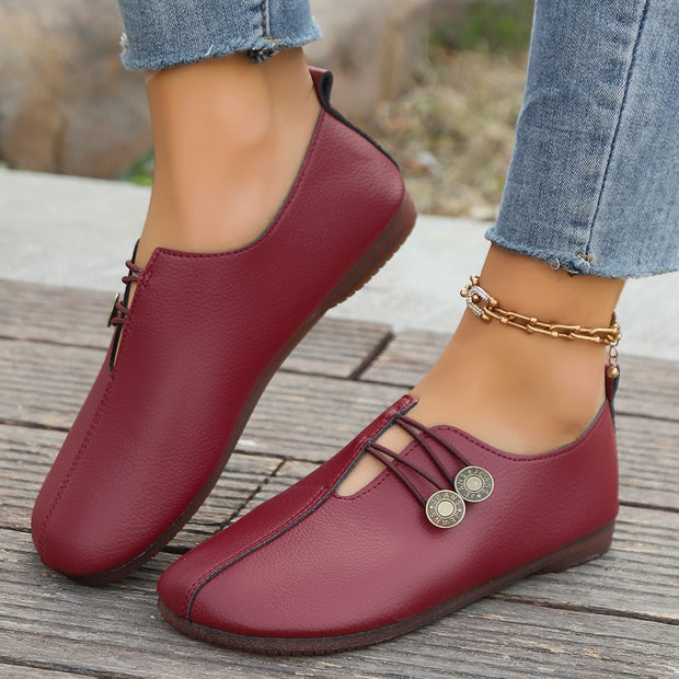 Red loafers worn with denim jeans on a wooden surface