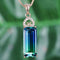 Jewelry pendant with a green gemstone on a blurred green background