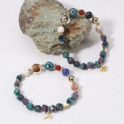 Multicolored beaded bracelet with gold accents on a textured stone surface