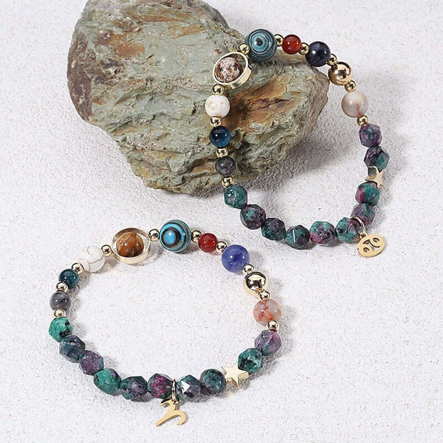 Multicolored beaded bracelet with gold accents on a textured stone surface