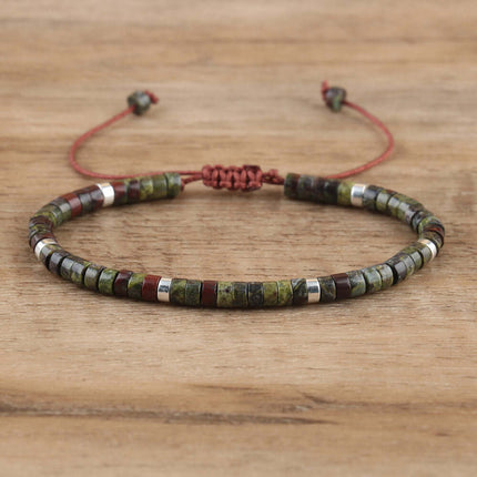 Adjustable women's bracelet featuring natural stone spacer beads in green and brown tones on a wooden background.