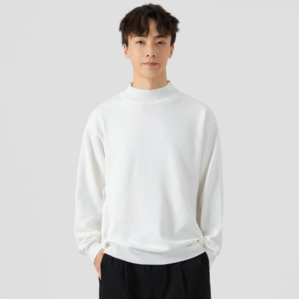 Man wearing a white sweater against a plain background