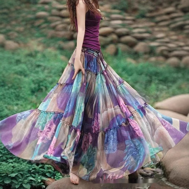 Woman wearing a colorful, flowing skirt outdoors with greenery and rocks in the background