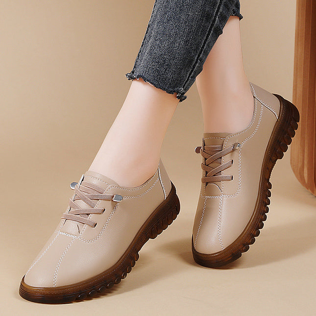 Beige leather shoes with brown soles worn by a person on a beige background