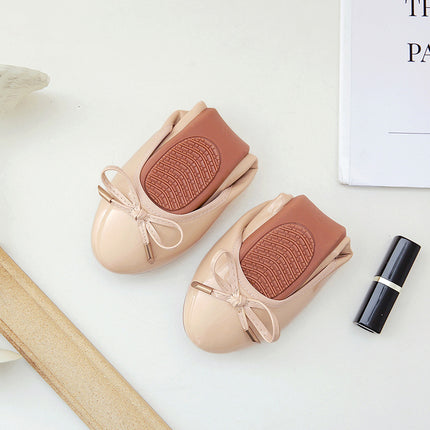 Foldable ballet shoes in nude color with soft bottom and flat heel, featuring a bow detail and designed for comfort.