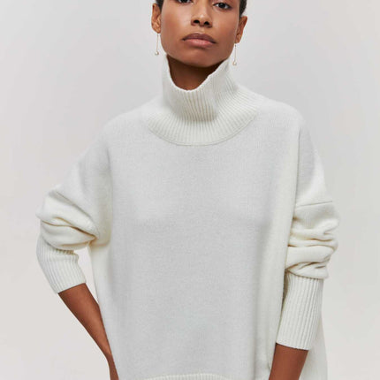 Person wearing a white turtleneck sweater against a plain background