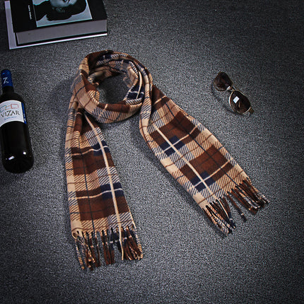 Plaid scarf with tassels on a textured surface next to a bottle and sunglasses.