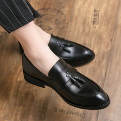 Black loafers with tassels worn on a wooden floor