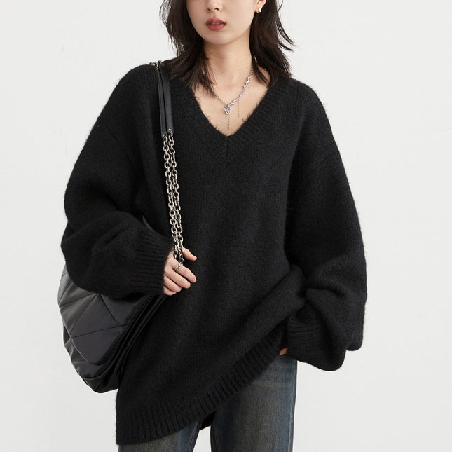 Person wearing a black oversized sweater holding a black bag on a light gray background