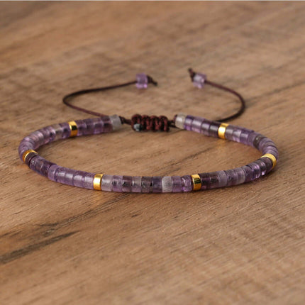 Hand-woven adjustable bracelet featuring purple amethyst beads and gold accents on a wooden background.