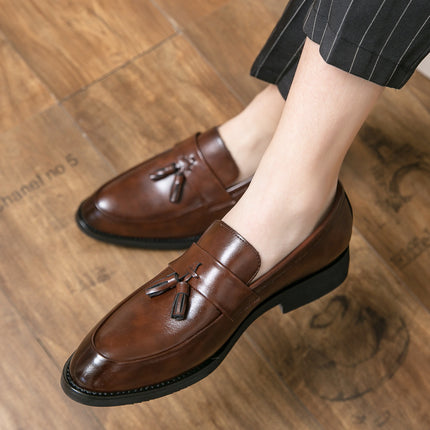 Brown loafers with tassels worn on a wooden floor