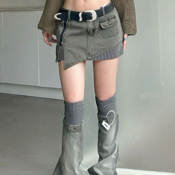Person wearing a gray denim skirt, knee-high boots, and a belt with a large buckle.