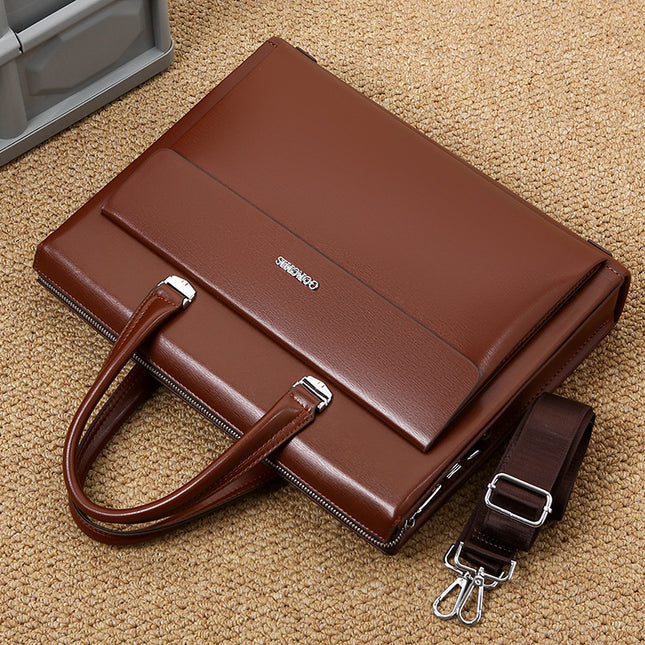 Brown leather briefcase with shoulder strap on a beige surface